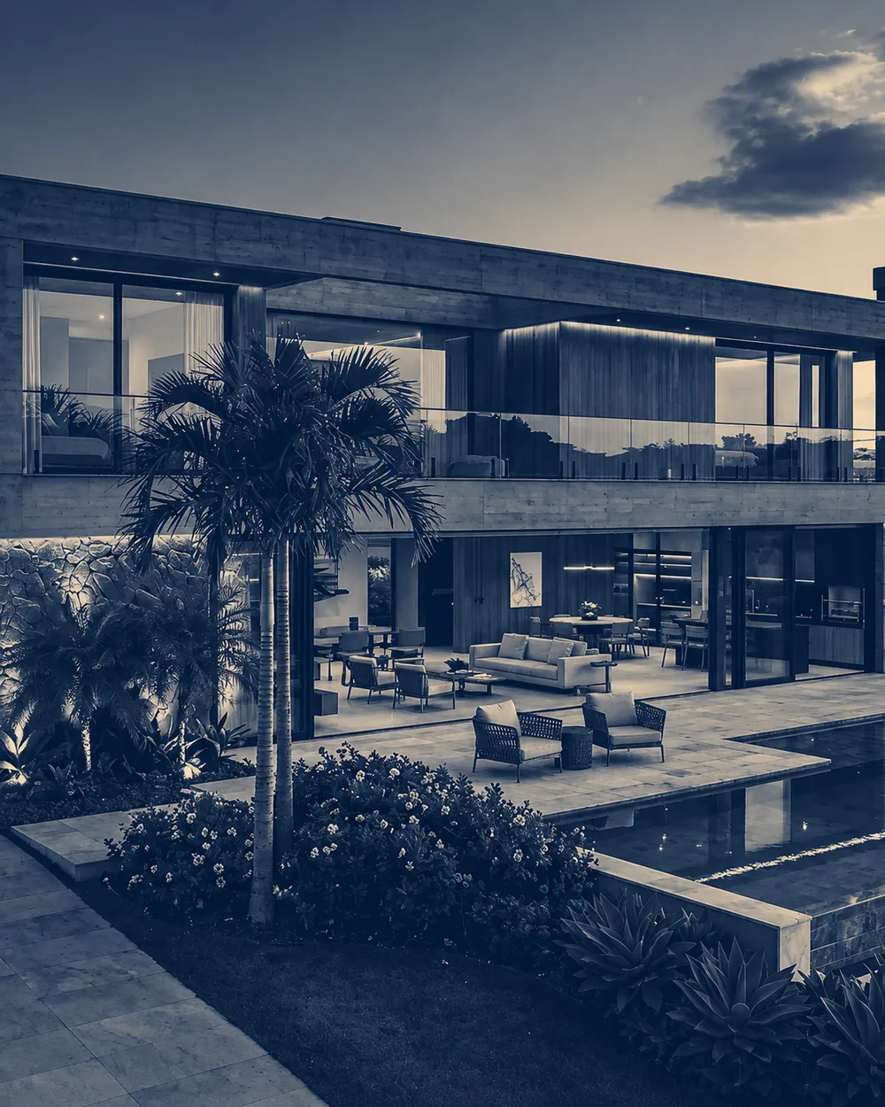 Fachada de residência de dois pavimentos em concreto aparente e madeira, com piscina, deck e jardim tropical ao entardecer