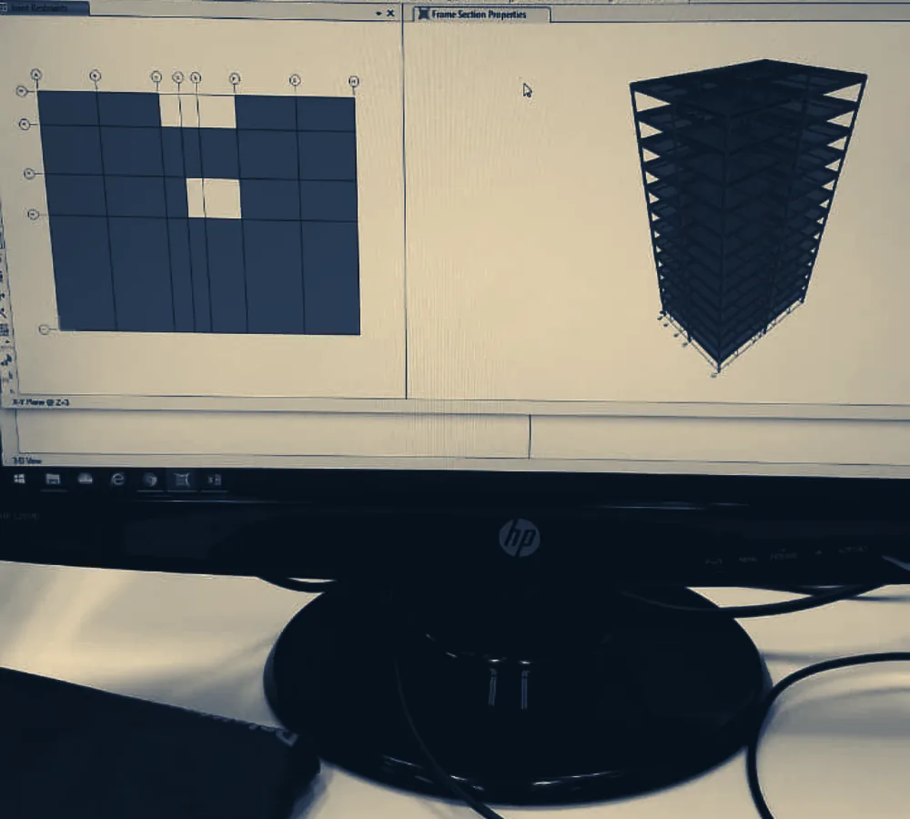 Monitor exibindo software de cálculo estrutural com planta de fôrmas e modelo tridimensional do edifício